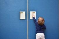 cute baby boy trying to open blue door